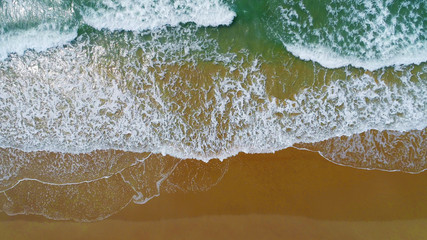 Beach on aerial drone top view with ocean waves reaching shore.