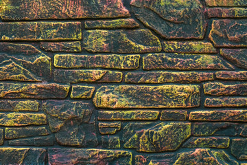 Multi colored brick wall. Fluorescent paint on abstract colorful background. Multicolor architecture texture. Motley decorative tile with luminous paint. Dark stone pattern.