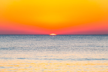 The last seconds of the amazing sundown behind the sea horizon. A bit of the sun star sphere showing up above the Tyrrhenian sea level. Vibrant sunset on Cala Violina beach