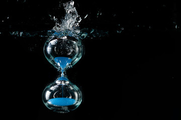 hourglass in water on black background