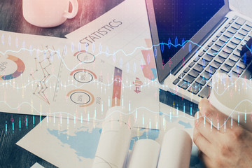 Double exposure of businessman's hands with laptop and stock market graph background. Concept of...