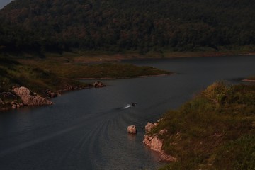 The boat is sailing on a river surrounded by mountains. Mae Kuang Dam, Chiang Mai, Thailand