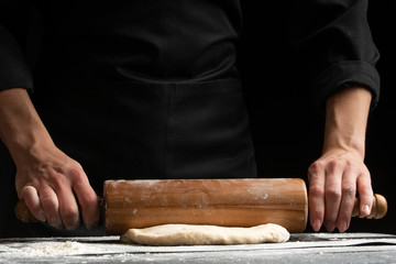 The chef cooks the dough under a rosquat press, for baking, bread, pizza, or pasta. on a black background