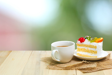 Slice cake with coffee cup on wood , green blur background