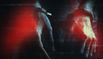 young man hand handcuffs on dark background