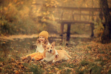 smiling girl embracing corgi dog in the park at fall time