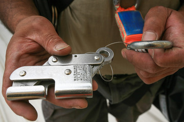 Male construction worker hand demonstration how to clipping industrial safety Karabiner connected with fall arrest shock absorbing safety lanyard device into stainless back up safety device 