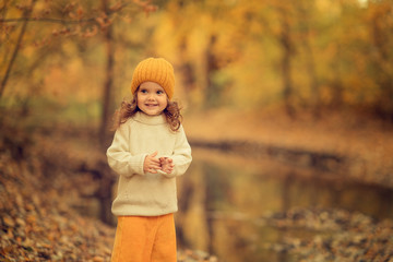 portrait of cheerful child standing in autumn park with blurred background