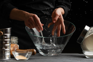 a pastry chef or baker prepares the dough by whipping with a spoon, for sweets, rolls or Italian...