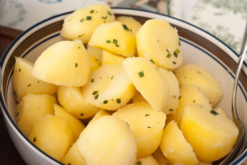 Naklejka na ściany i meble Boiled and sliced potatoes served in a bowl with herbs on top.