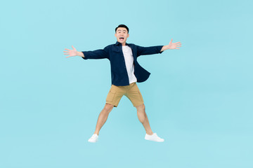 Young dynamic Asian man looking amazed jumping in midair