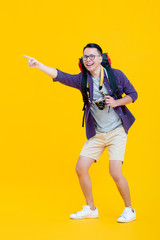 Fototapeta na wymiar Young happy Asian male backpacker smiling and pointing while holding camera