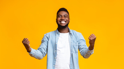 Joyful black guy rejoicing success with clenched fists