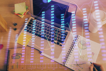 Double exposure of man's hands writing notes of stock market with forex chart.
