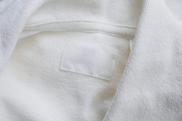 Blank white clothes label on new cotton shirt background