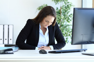 Young businesswoman suffering bellyache at office