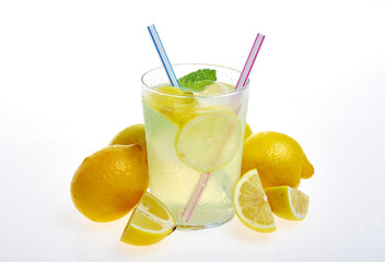 Front view of yellow lemons with lemonade glass with ice on a white background