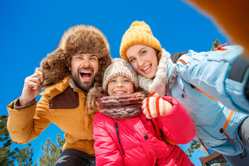 Winter vacation. Family time together outdoors taking selfie shhowing thumbs up smiling toothy bottom view