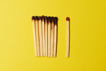 Symbol of danger with matches on yellow  background top view , pile of match arrange in a row with one  unBurnt match , unlit matches , unique and various concept