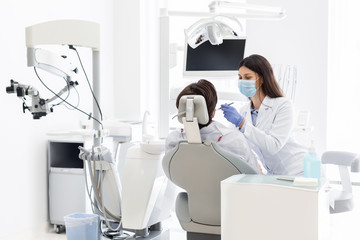 Naklejka premium Pretty dentist doctor treating patient in dental clinic