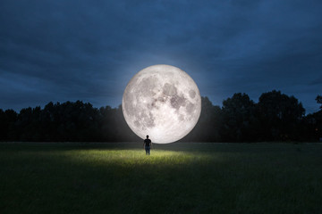 Man standing in front of the Moon. Elements of this image furnished by NASA. - obrazy, fototapety, plakaty