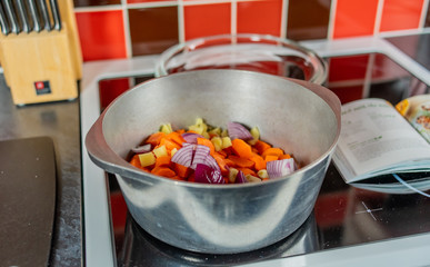 Selective focus on a portion of carrots, ginger, onion and garlic in a stainless-steel saucepan ready for boiling and turning in to a healthy and homecooked soup