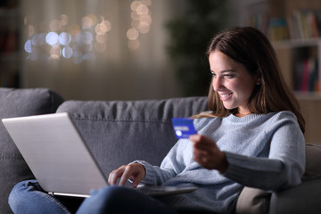 Happy woman in the night buying on line at home