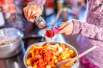  Home chef adding a spoonful of tomato puree to make a nutritious and healthy homecooked vegetarian and vegan Spanish paprika stew