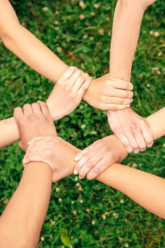Volunteering. Young people volunteers outdoors together holding hands unity top view close-up
