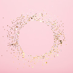 Round copy space of gold confetti on pink background
