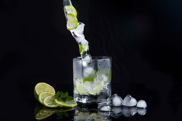 Summer cocktail mojito with splash on black background..