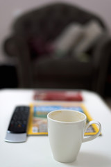 White cup of coffee and tv remote controller