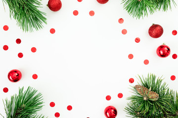 Fototapeta na wymiar Christmas frame of pine branches and red balls decoration with confetti on white background.