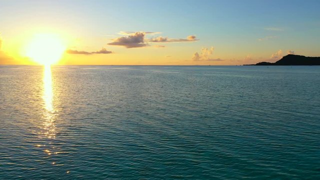 Aerial of an amazing sunset over the ocean, drone flying forward then turning from right to left while ascending - Bora Bora, French Polynesia