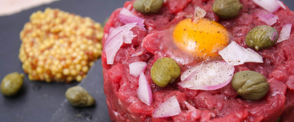 Steak tartare of raw minced meat with salt and spices, on a black stone