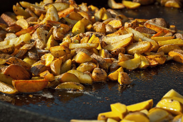 Roast potatoes in a large pan. Delicious food at the festival. Field kitchen at the hearth.