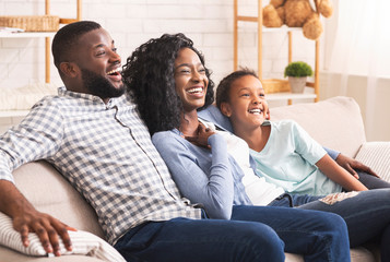Joyful african american family watching comedy show on tv together