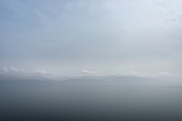 Mountainous shore of the Dead Sea hidden by a haze.