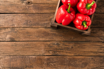 Overhead shot of red sweet paprika in box on old wooden background with copyspace. Bell pepper. Top...