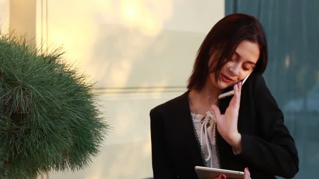Black haired girl.Business woman in black classic suit.White blouse.Fashion style.Working with phone and tablet.