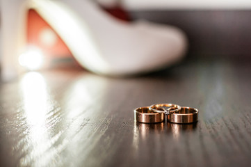 Three gold wedding rings and white high heel shoe on the table
