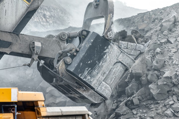 Powerful and large excavator bucket. Loading of minerals into the body of a mining truck.