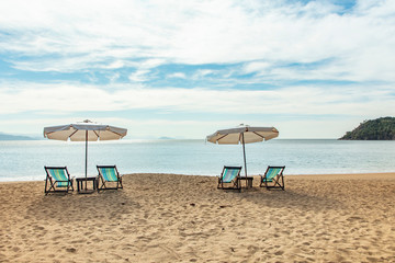 Beautiful panoramic view of Jabaquara beach in Ilhabela with chairs and umbrella on tropical island on the Brazilian sea coast during a sunny day of vacation and sightseeing trip.