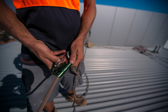 Rope access industry worker inspecting clipping rope into advantage mechanical pulley system prior used on construction building site in Sydney city CBD, Australia