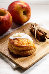piece of cinnamon apple pie on a wooden board with fresh apple in background, autumn food concept