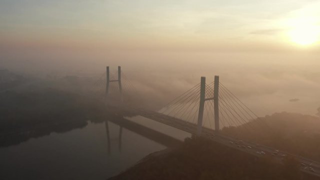 Aerial. Siekierkowski Bridge in foggy weather. Warsaw at sunrise. Poland. Drone shot at the traffic of vehicle traveling in traffic jam on a bridge over a river. Drone Shot 4K.