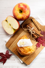 piece of cinnamon apple pie on a wooden board with fresh apple in background, autumn food concept