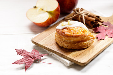 Obraz na płótnie Canvas piece of cinnamon apple pie on a wooden board with fresh apple in background, autumn food concept