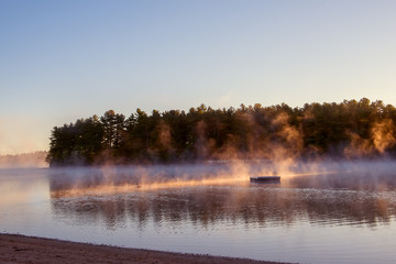 Fototapeta na wymiar A gentle morning on the lake with fog over the water in the sun. USA. Maine