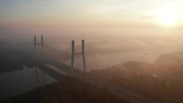 Aerial view of the Siekierkowski Bridge in beautiful fog. Warsaw, Poland. Drone shot at the traffic of vehicle traveling in traffic jam on a bridge over a river.